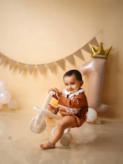 A happy one-year-old on her wooden tricycle, part of a charming teddy bear-themed birthday setup. I have a wide range of props to suit any theme.