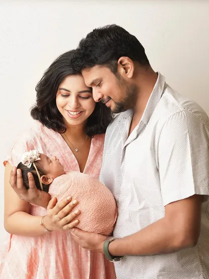Parents holding their newborn, their heads close together. This pose creates a beautiful sense of intimacy and shared love for their baby.