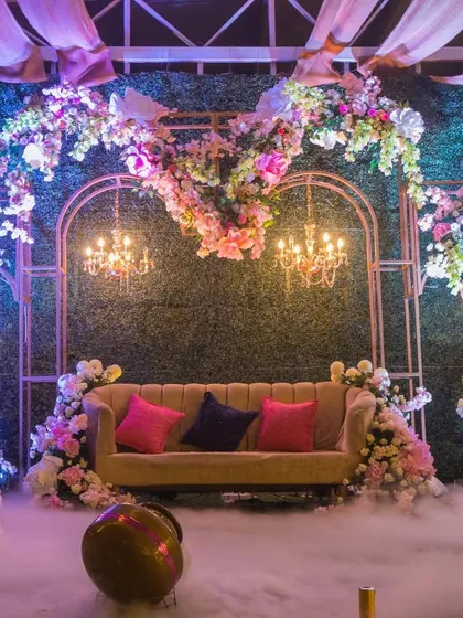 A dreamy stage setup for an evening reception, with a heart-shaped floral arrangement, elegant chandeliers, and a mystical fog effect.