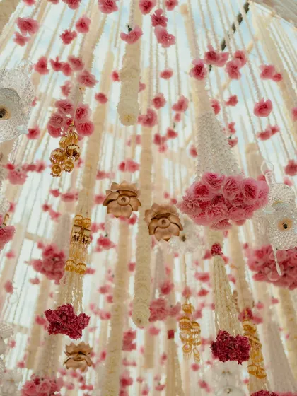 A close-up, upward view of the hanging floral tassels made of tuberose and pink roses, showcasing the intricate and delicate craftsmanship of the mandap ceiling.