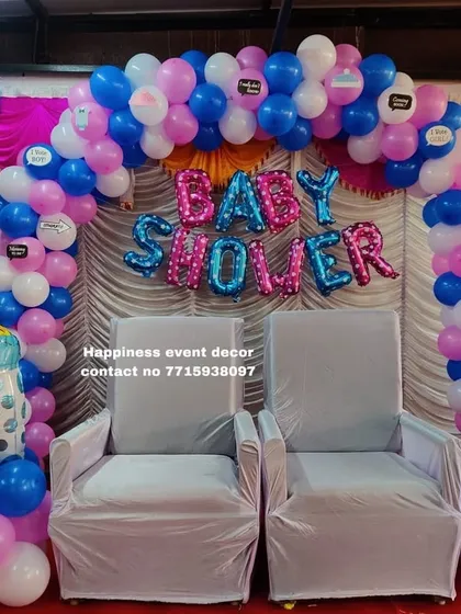 A simple yet beautiful baby shower decoration with a balloon arch in pink, blue, and white. The 'BABY SHOWER' foil balloons and baby bottle cutouts clearly mark the happy occasion.