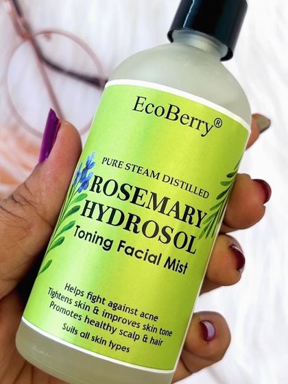 A detailed shot of our Pure Steam Distilled Rosemary Hydrosol. The label clearly states its benefits: fights acne, tightens skin, improves tone, and promotes a healthy scalp and hair.