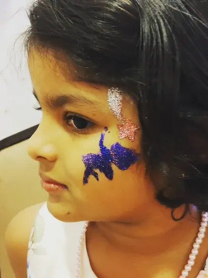 A sweet and simple cheek art design featuring a small angel and shooting stars. This kind of quick, charming body art is perfect for larger parties so everyone gets a turn.