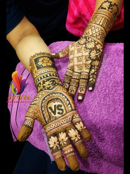 A beautiful engagement mehndi with the couple's initials 'VS' prominently featured. The design is filled with lotus flowers and traditional patterns.