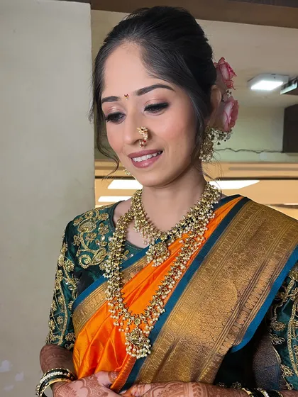 This pose highlights the floral bun and the intricate pearl jewelry.