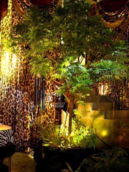 Lush greenery and warm uplighting against a backdrop of leopard-print drapery, adding a touch of the jungle to the opulent theme.