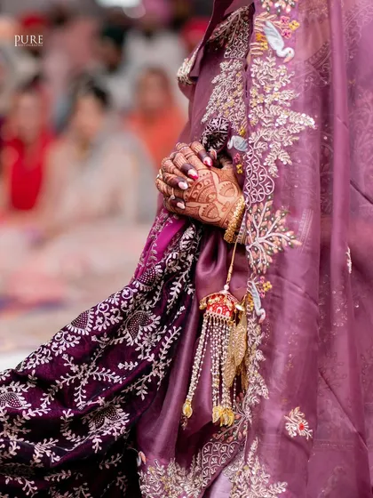 A close-up detail shot of the bride's hands during the ceremony. This photo highlights her intricate henna and the beautiful embroidery of her wedding lehenga.