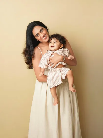 A mother and her toddler son share a joyful moment. The warm, neutral background and their happy expressions create a timeless and heartwarming portrait.