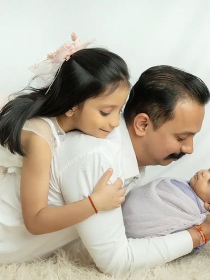 The bond between a father and his two daughters is so special. The older sister joins in for a loving family photo.