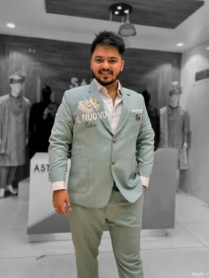 A client in a light blue-grey suit with subtle custom embroidery on the lapel. This is a great example of a personalized business or event suit.