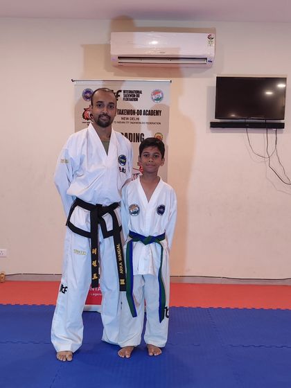 A student receives his blue-stripe belt, marking his advancement in the Taekwon-Do journey.