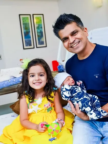 A proud father and big sister pose with the newest member of their family in the hospital room.