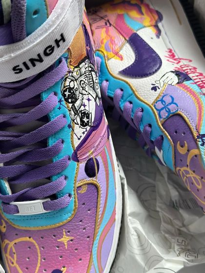 A close-up of the BTS-themed custom Air Force 1s. You can see the intricate details of the astronaut riding the whale through a cosmic sky.