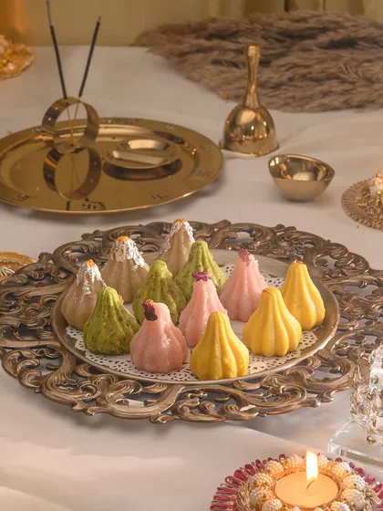 An array of my artisanal modaks in different flavours and colours, beautifully arranged on a vintage-style platter with puja essentials.