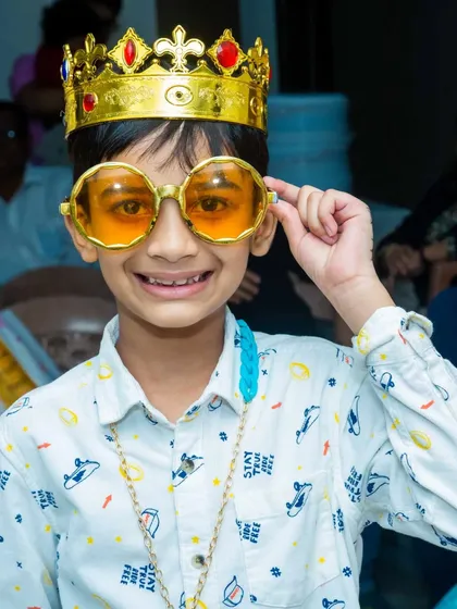 A young guest feeling like royalty with a golden crown and oversized glasses. These simple props can make any child feel like the star of the show.