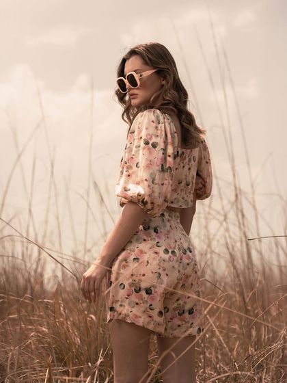 This over-the-shoulder pose highlights the back of the puff-sleeve top and the fit of the shorts. It provides a different view of the outfit while maintaining a chic, editorial feel.