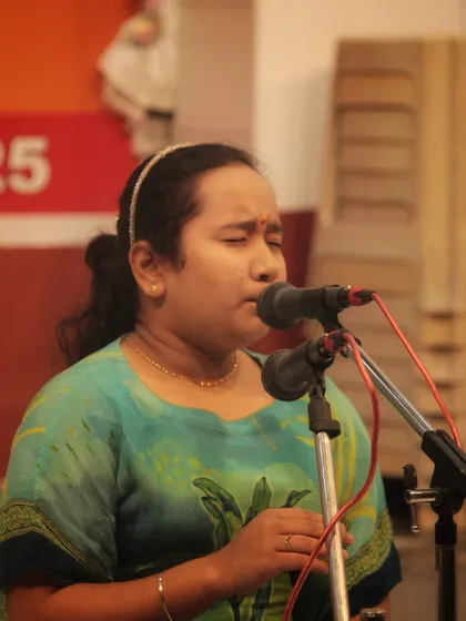 A student singing with her eyes closed, completely connected to the notes and the emotion of the bhajan.