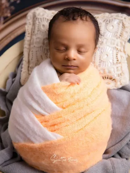 A detailed shot of the baby in the bowl, showing the texture of the wrap and the peaceful expression.
