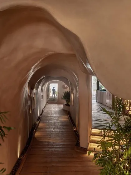 The entrance to Dubki is through a cave-like tunnel constructed from ferro-cement. This design creates a sense of discovery, as the narrow, earthy passage opens up to the expansive, bright view of the beach.