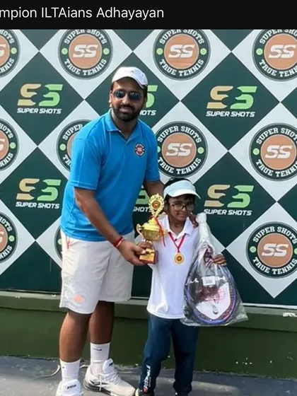 Champion Adhyayan with his coach and trophy after a win. This one on one encouragement is a key part of how we build confident players.