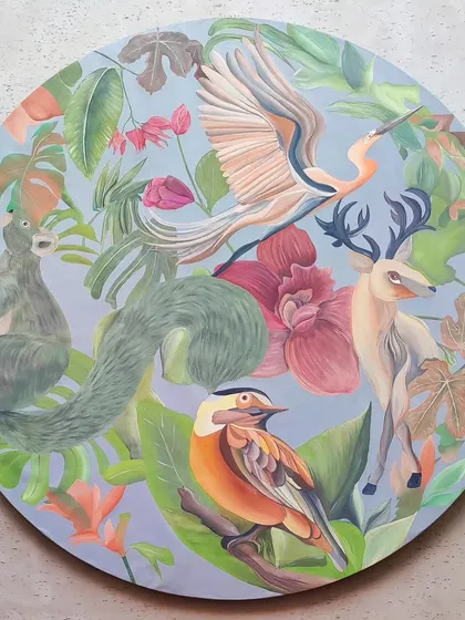 A large, circular canvas featuring a vibrant scene of animals in a tropical forest. This piece was created as a statement artwork for a residential courtyard.