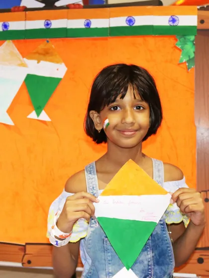 A girl with a tricolor painted on her cheek shows off her handmade kite. Face painting and themed crafts are some of the most popular activities during our festive events.