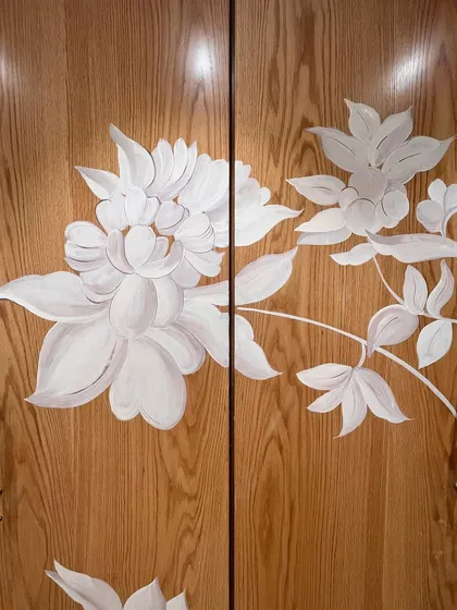 Another section of the hand-painted wardrobe, where the delicate white flowers contrast beautifully with the warm grain of the wood.
