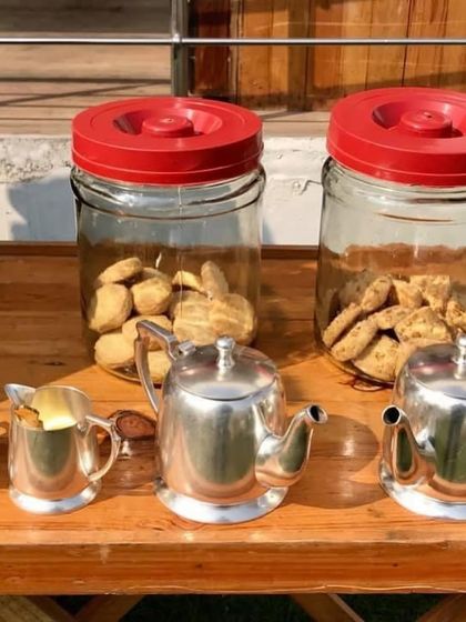 A charming high-tea setup at a spring farm party. The silver teapots and glass jars filled with cookies add a touch of vintage elegance.