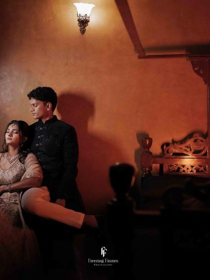 A moody, atmospheric shot of the couple in a dimly lit room with traditional decor.