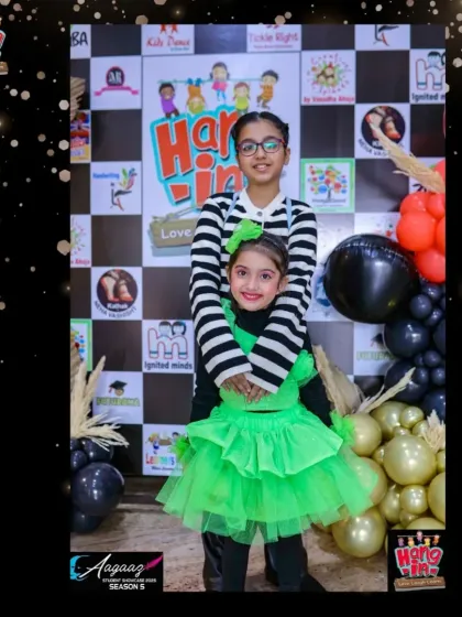 A proud moment for our little performer in her bright green costume, posing with her sister. Aagaaz is a family affair, and we love the support they show.