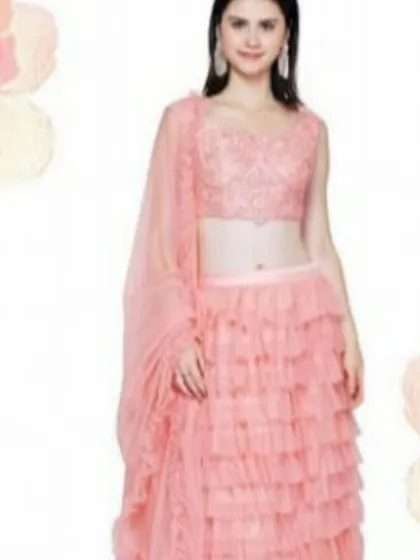Embrace a playful and trendy style with this peach lehenga featuring a multi-layered ruffled skirt. Paired with a beautifully embroidered sleeveless blouse and a sheer dupatta, this outfit is a youthful and fashionable choice for daytime weddings or festive events.