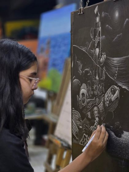 A student at her easel, focused on creating her large-scale glass marking pencil drawing. The studio environment encourages such dedicated and ambitious projects.