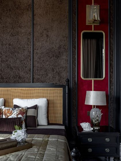We believe in creating interiors with depth and character. This bedroom features a bold red accent wall paired with dark wood panelling and custom lighting, crafting a space that is intimate, luxurious, and highly personal.