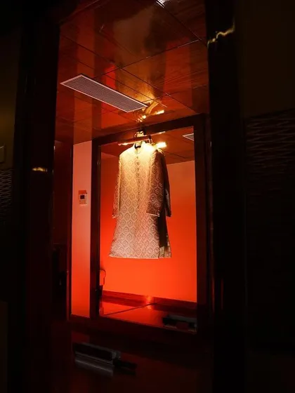 An artistic shot of the groom's sherwani hanging in a room with dramatic red lighting. We find creative ways to photograph every element of the wedding.