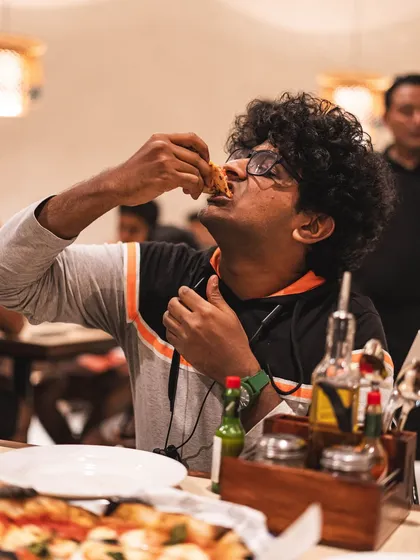 Pure enjoyment. A customer savors a slice of our pizza, completely lost in the flavor.
