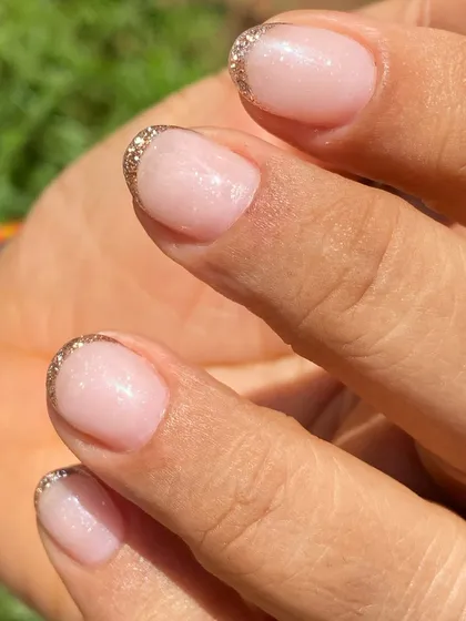 A simple yet glamorous look for short nails. This is a sheer nude overlay with a delicate gold glitter French tip.