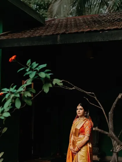 A bride stands against a dark background, the dramatic lighting highlighting her features and the details of her attire.