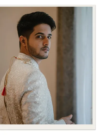 A classic groom portrait by the window, capturing his thoughtful expression as he looks back.