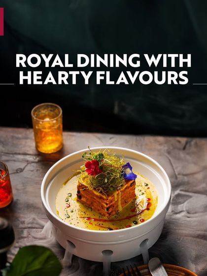 Royal dining with hearty flavours at Khubani. This image of an elegantly presented dish with edible flowers and smoke effects showcases the fine dining and artistic culinary experiences available.