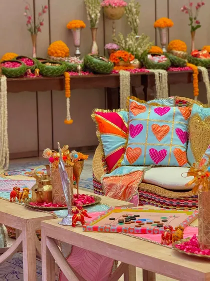 Another angle of the playful seating area, showing the custom-printed cushions and the decorated carrom board. The background features a table laden with floral arrangements and festive treats.