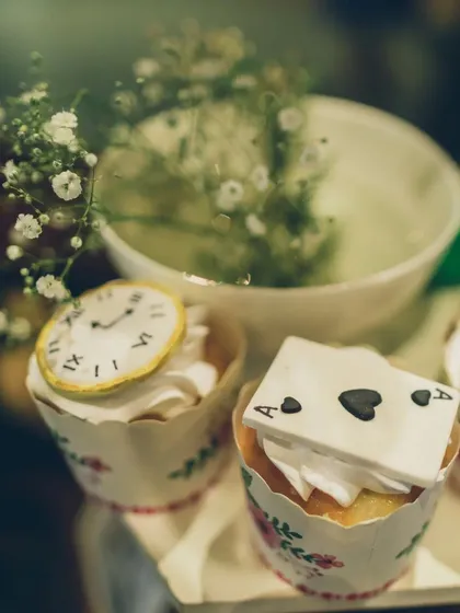 Themed desserts are a must. These cupcakes are topped with intricate, edible fondant decorations, including a tiny clock and an ace of spades playing card, perfectly fitting the Wonderland theme.