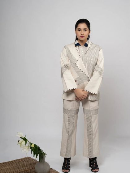 A clean and minimalist full-length portrait. This shot showcases the unique patchwork design and sharp tailoring of this contemporary pantsuit against a simple studio background.