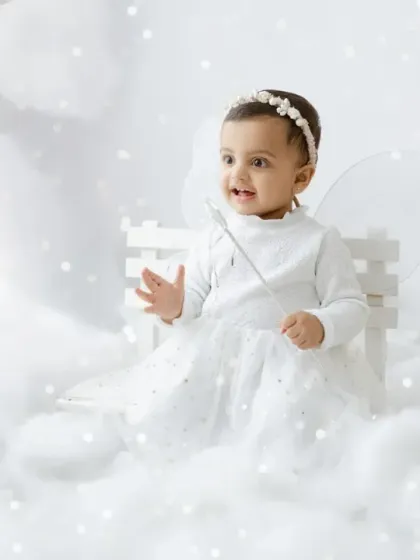 Our little fairy, complete with wings and a magic wand, sitting on a tiny white bench in her cloud kingdom.