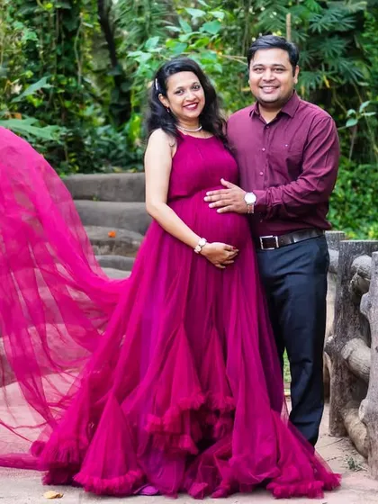 The wind catches the train of this magenta gown, creating a beautiful, flowing effect as the couple stands on a small bridge.