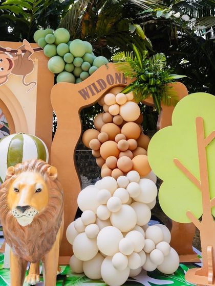 A "Wild One" party setup featuring a lion prop and a balloon arch, creating a fun and adventurous photo corner.