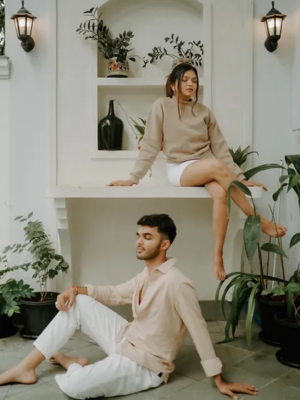 A stylish, relaxed portrait taken at a villa in Goa. The neutral-toned outfits and lush green plants create a modern and serene aesthetic for this pre-wedding shot.