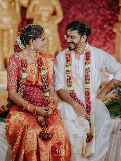 A candid moment of the couple sharing a smile while seated during their wedding ceremony.