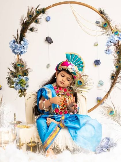 A full view of the ethereal Janmashtami setup, featuring a large ring decorated with peacock feathers and flowers.