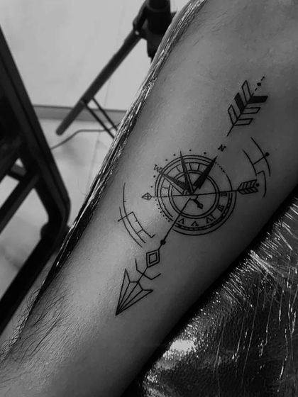 A geometric compass and arrow tattoo on the forearm. This design combines clean lines and symbols of direction and purpose.