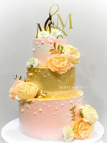 This elegant three-tier wedding cake features a beautiful blend of peach and gold tones, adorned with delicate sugar flowers. It’s a perfect example of how I create stunning, eggless centerpieces for your most special day, built sturdy enough to travel anywhere in Mumbai.